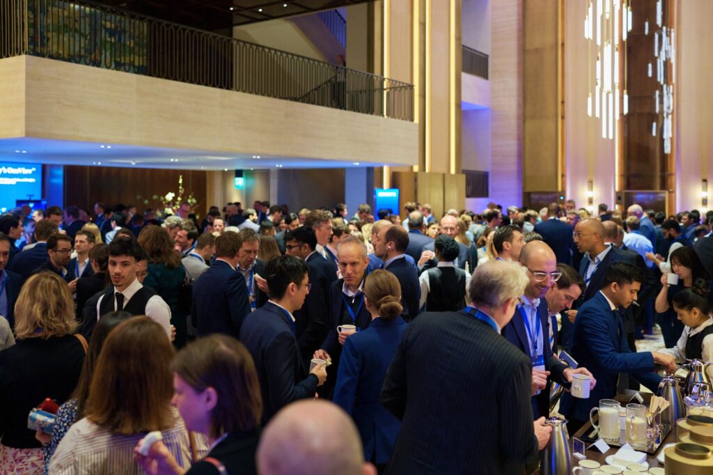 Crowd of people in corporate attire milling around an event room
