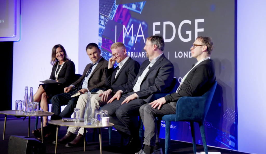 conference panel with five corporate speakers sat on a stage smiling