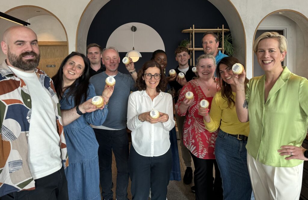 Group of people in office holding cupcakes